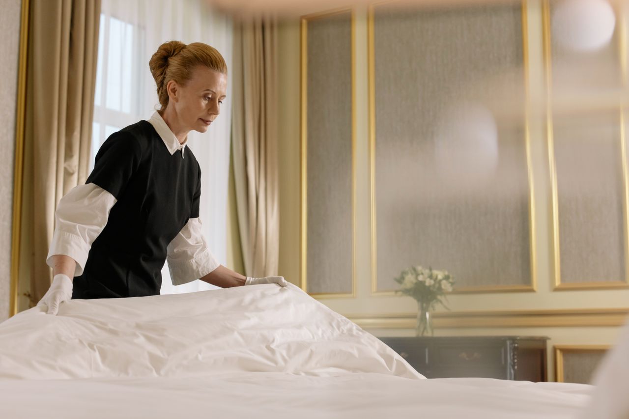 Une femme de chambre professionnelle refait un lit dans une chambre d'hôtel luxueuse.